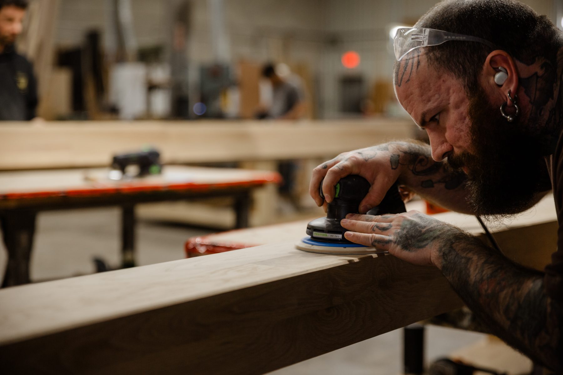 Mains d'un artisan guidant la ponceuse le long d'un chant